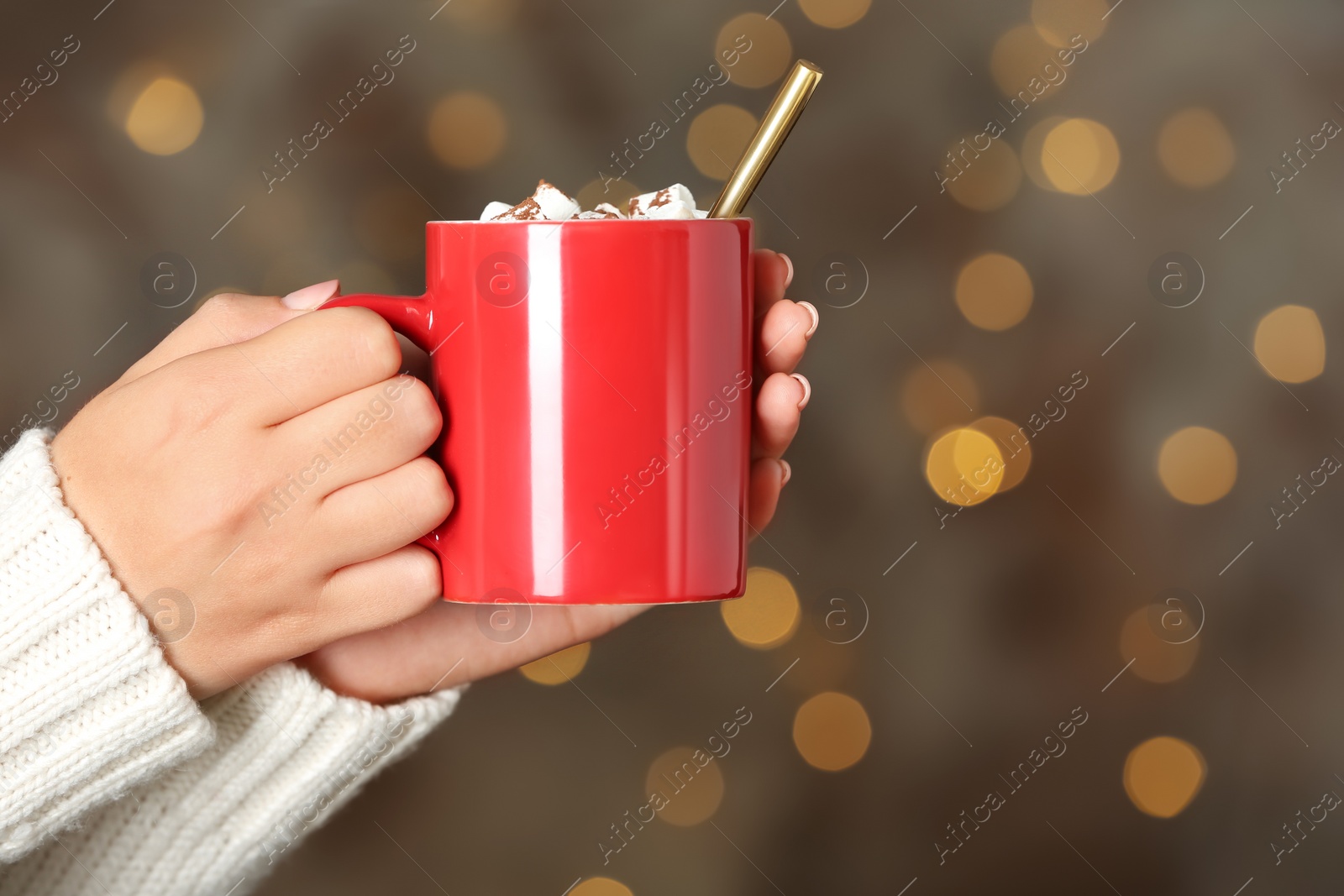 Photo of Woman holding cup of tasty cocoa with marshmallows on blurred background, closeup