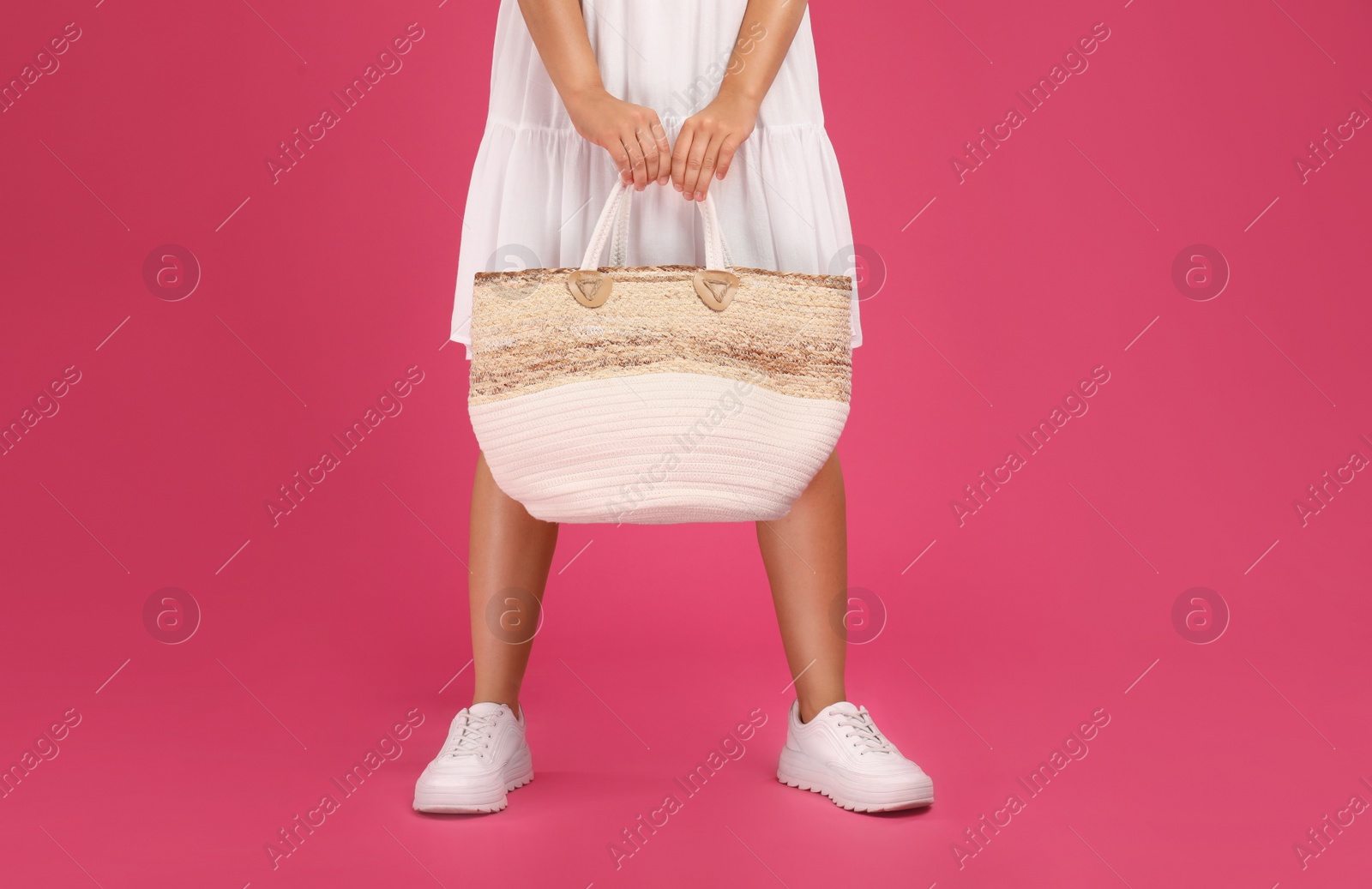 Photo of Young woman with stylish straw bag on pink background, closeup