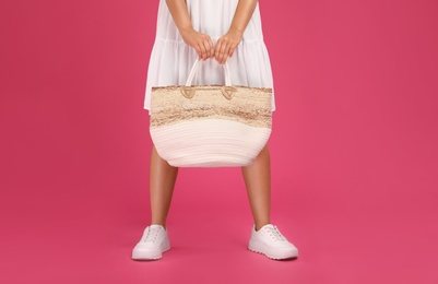 Young woman with stylish straw bag on pink background, closeup