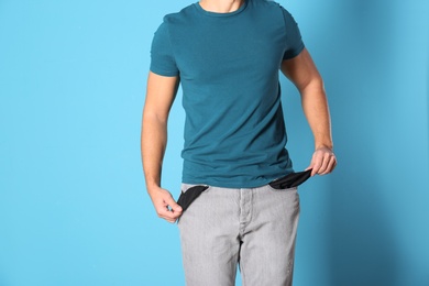 Man showing empty pockets on color background, closeup