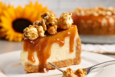 Photo of Piece of delicious caramel cheesecake with popcorn on plate, closeup