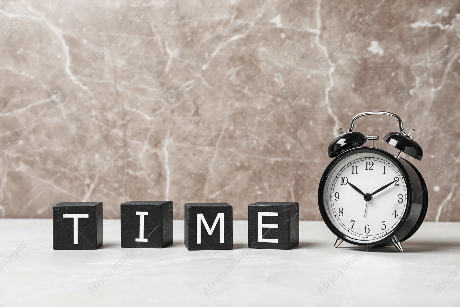 Photo of Alarm clock and cubes with word TIME on table