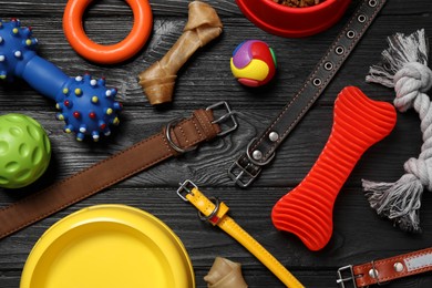 Photo of Flat lay composition with dog collars, toys and bowl on black wooden table