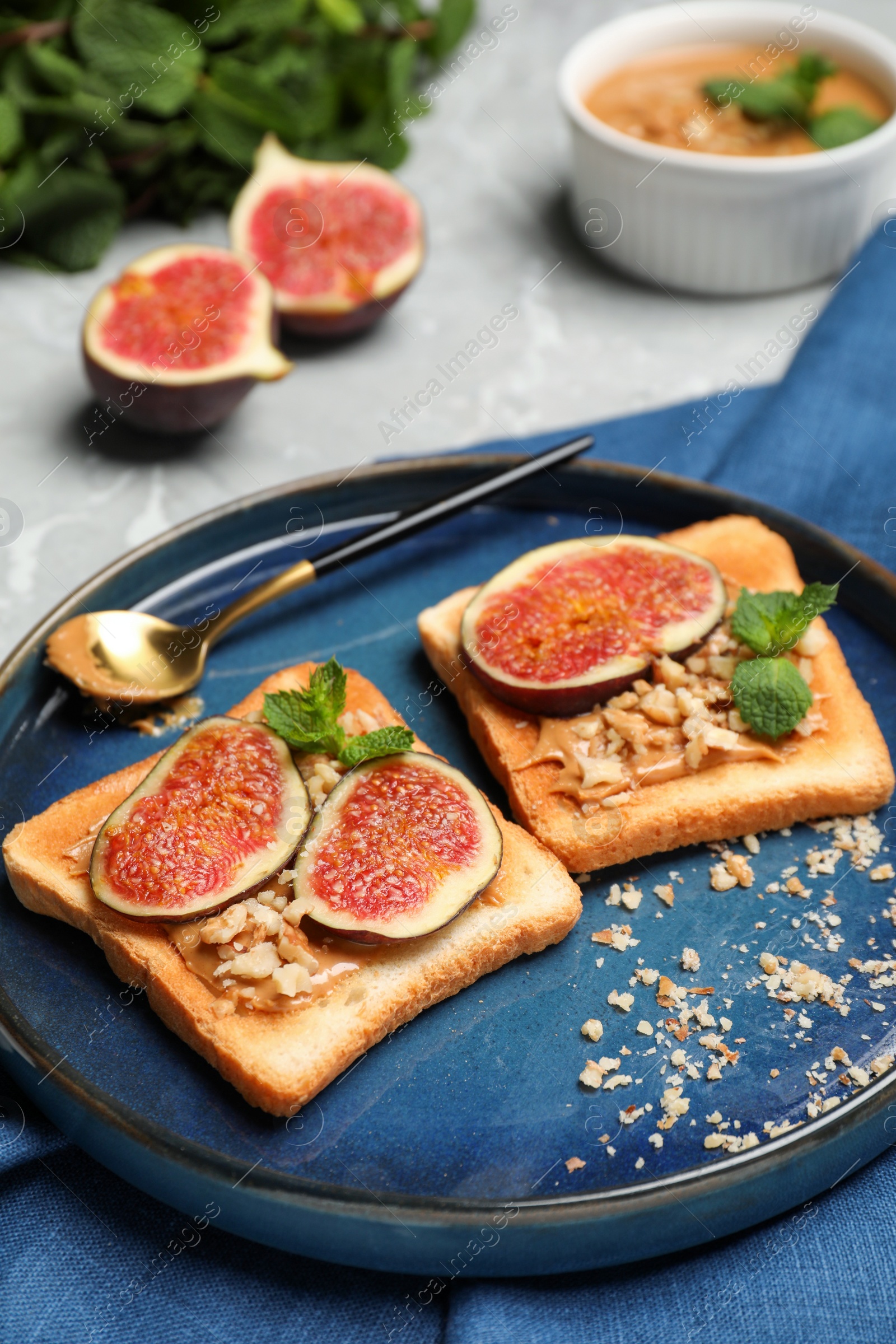 Photo of Tasty toasts served with fig, peanut butter and walnuts on light grey marble table