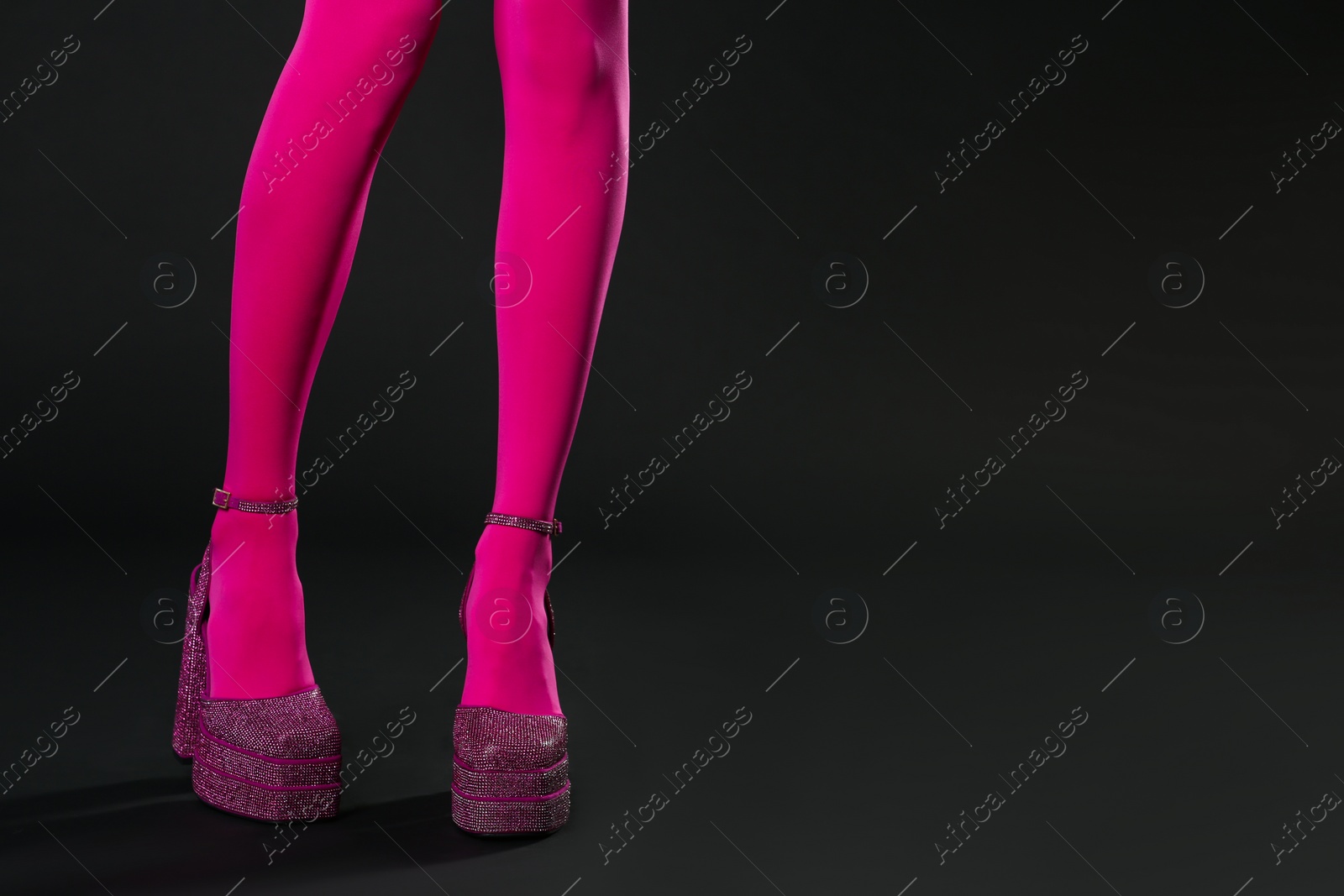 Photo of Woman wearing pink tights and high heeled shoes with platform and square toes on black background, closeup. Space for text