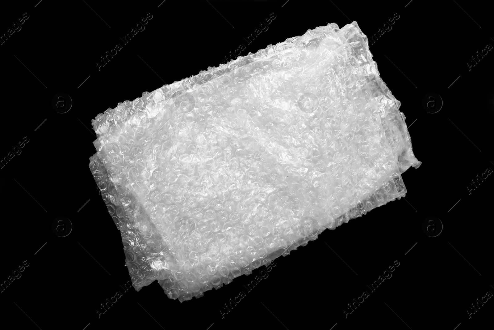 Photo of Folded transparent bubble wrap on black background, top view