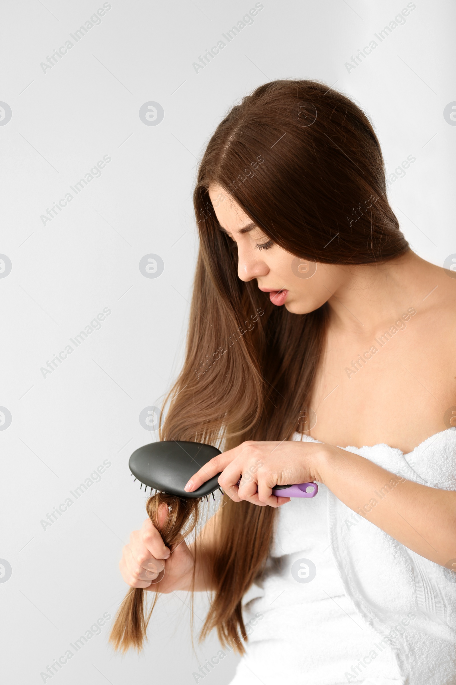 Photo of Woman struggles to brush her hair on light background