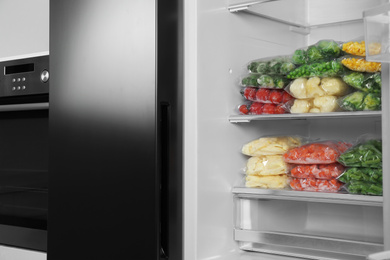 Plastic bags with different frozen vegetables in refrigerator indoors