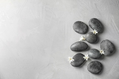 Photo of Zen stones and exotic flowers on grey background, top view with space for text