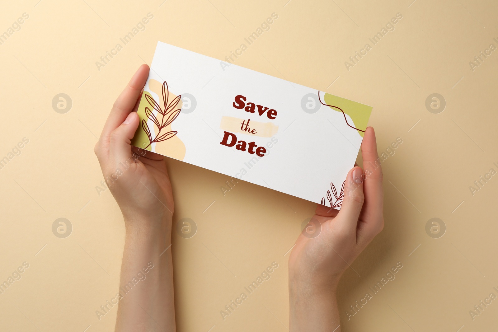 Photo of Woman holding beautiful card with Save the Date phrase on beige background, top view