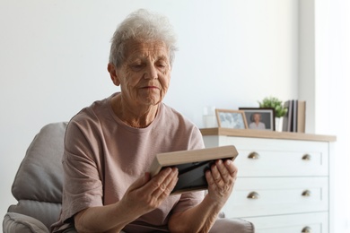 Photo of Elderly woman with framed photo at home