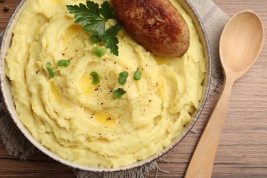 Bowl of tasty mashed potatoes with parsley, black pepper and cutlet served on wooden table, flat lay