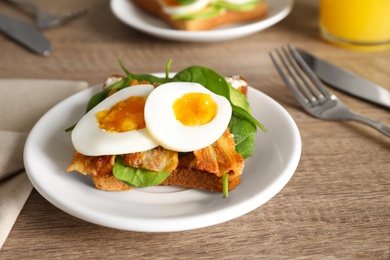 Photo of Sandwich with egg, bacon and spinach served on wooden table, closeup