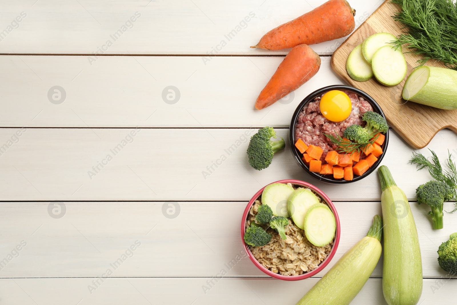 Photo of Pet food and natural ingredients on white wooden table, flat lay. Space for text