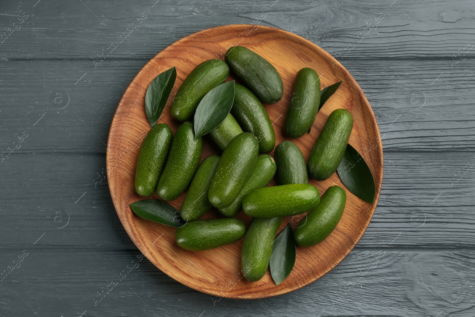 Photo of Fresh seedless avocados with green leaves on grey table, top view