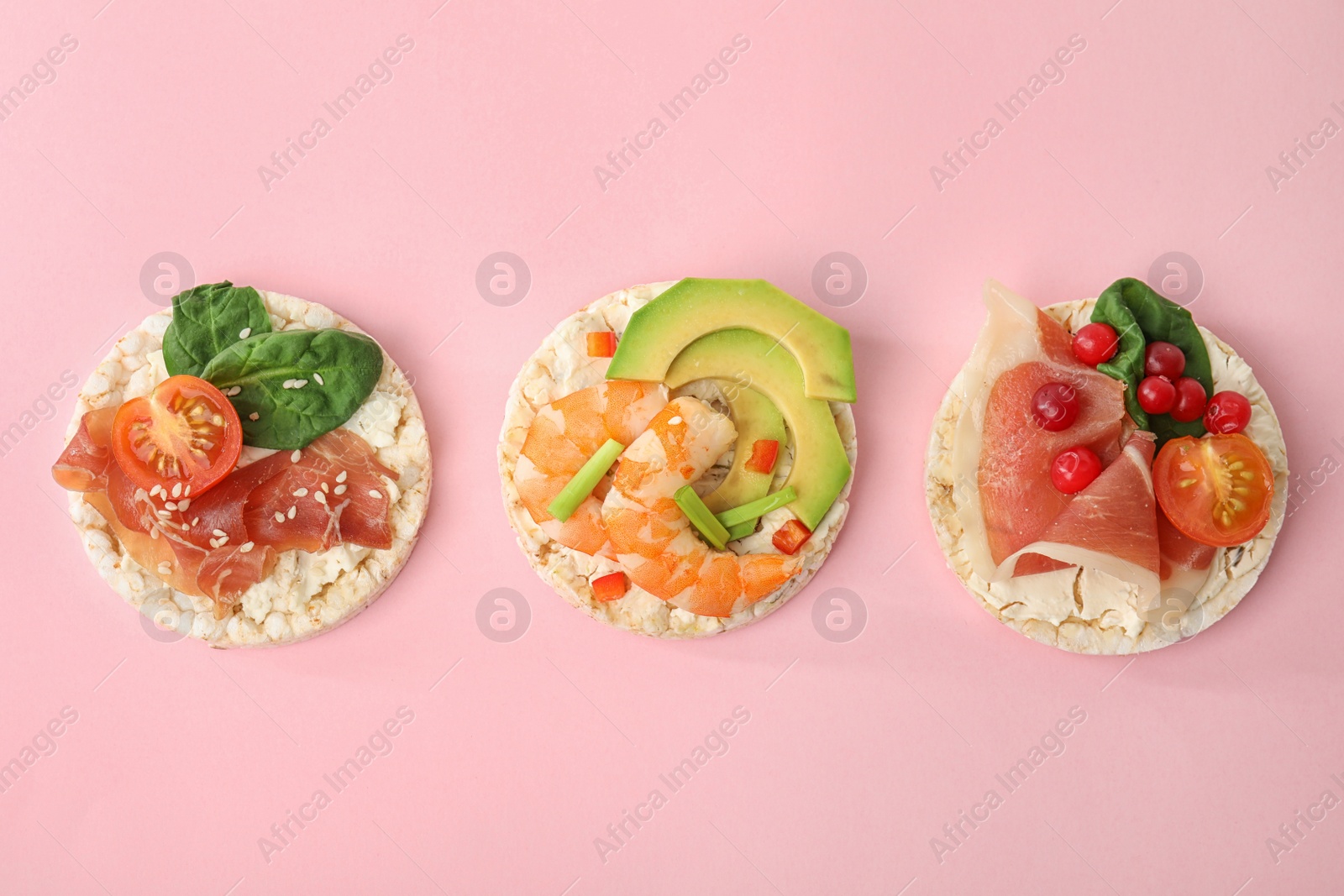 Photo of Puffed rice cakes with different toppings on pink background, flat lay