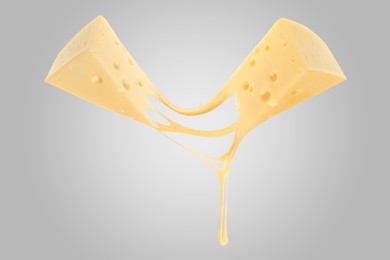 Tasty cheese stretching in air on grey background