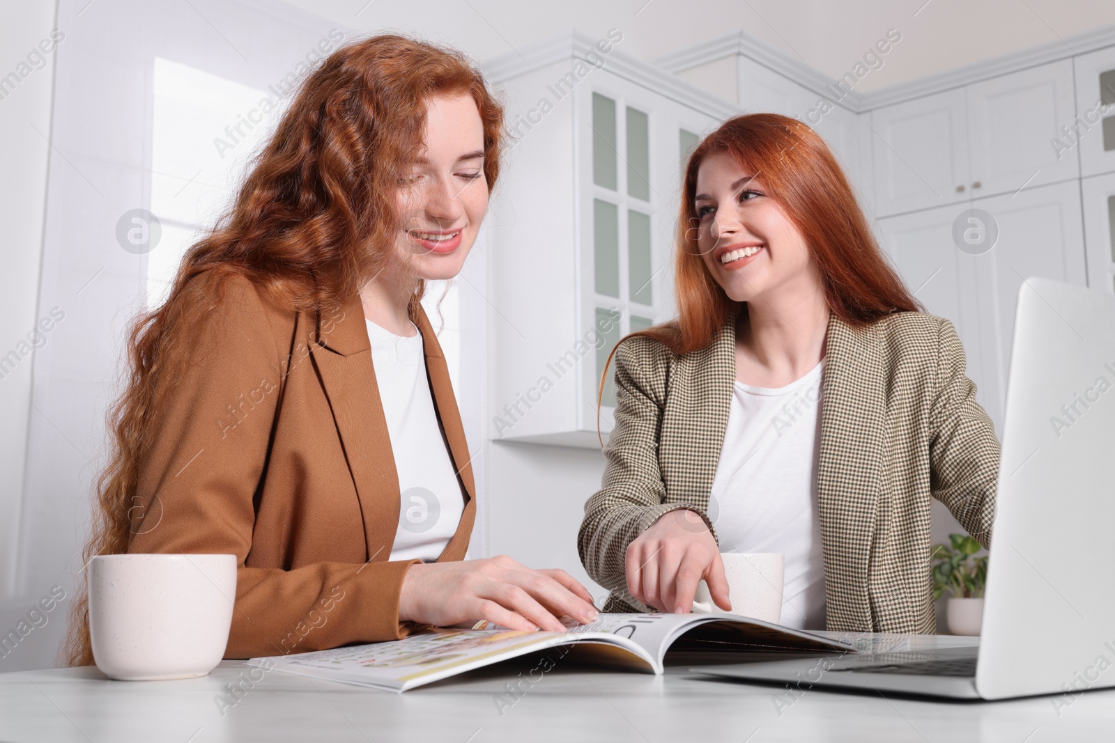 Photo of Beautiful young sisters spending time together in kitchen