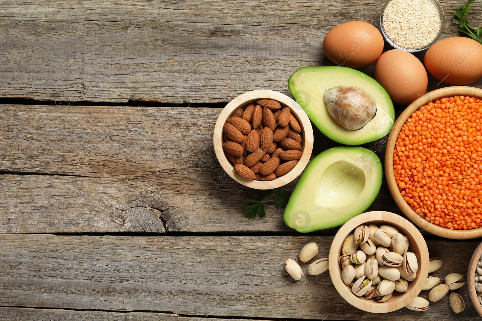 Photo of Different products high in natural fats on wooden table, flat lay. Space for text