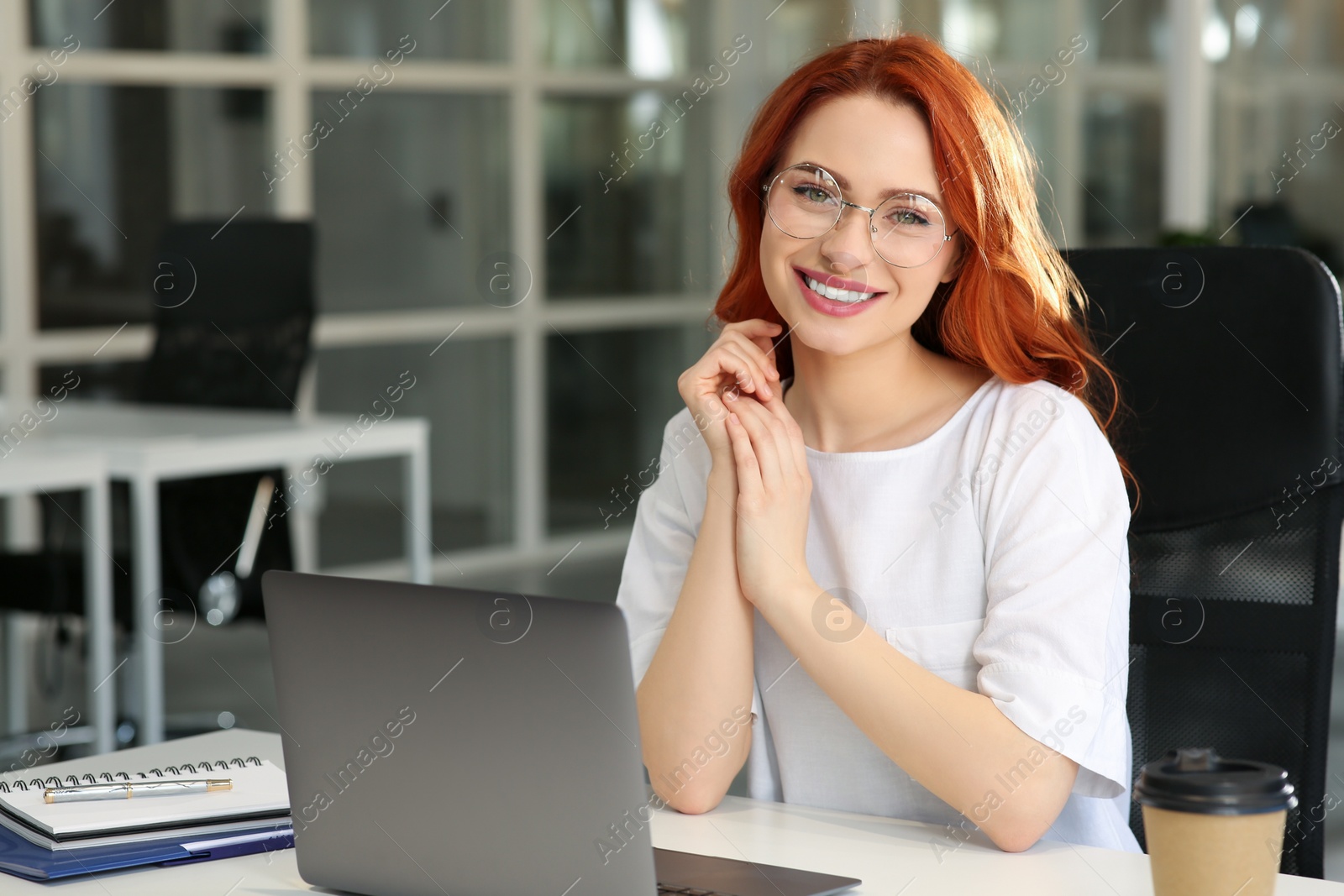 Photo of Happy woman working with laptop at white desk in office