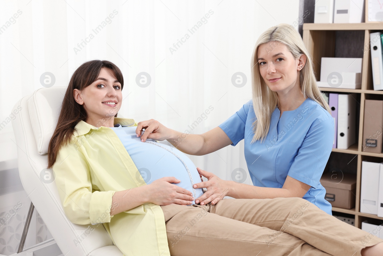 Photo of Pregnancy checkup. Doctor measuring patient's tummy in clinic