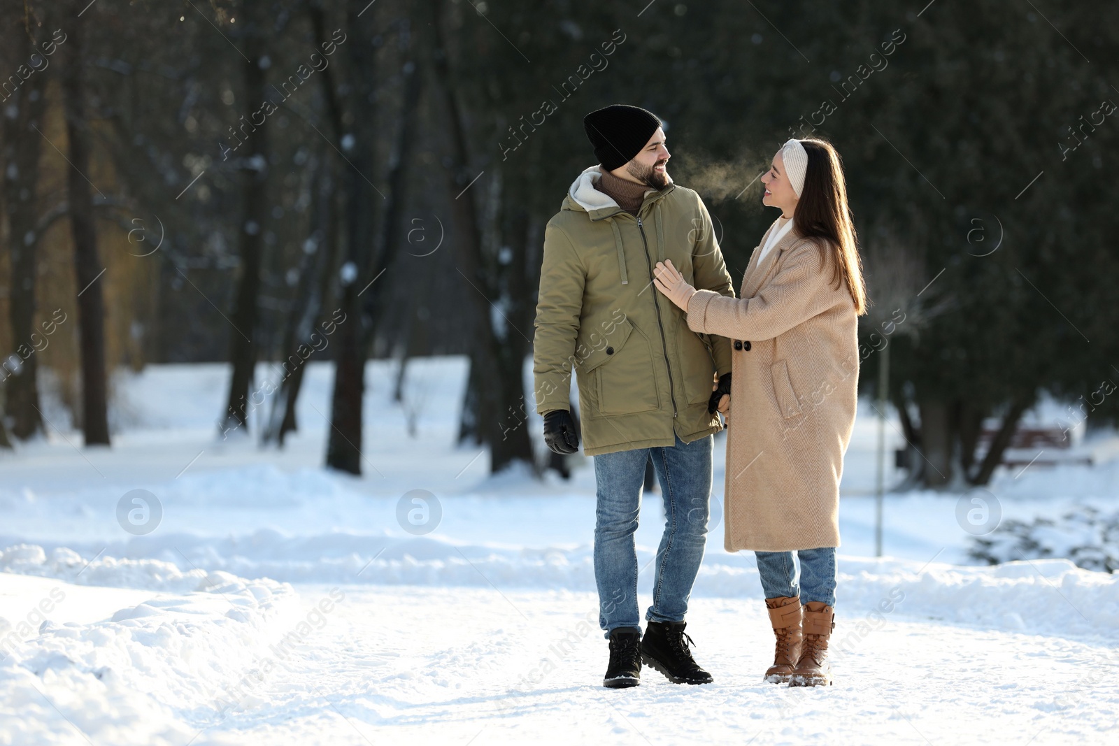 Photo of Happy young couple walking in snowy park on winter day