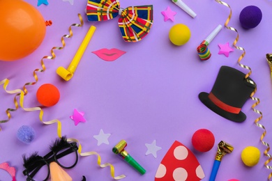 Photo of Frame made of clown's accessories on violet background. Space for text