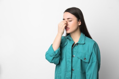 Photo of Young woman suffering from runny nose on white background. Space for text