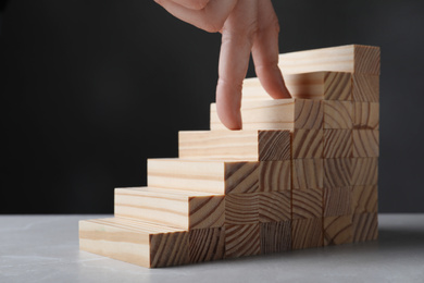 Photo of Woman imitating stepping up on wooden stairs with her fingers, closeup. Career ladder