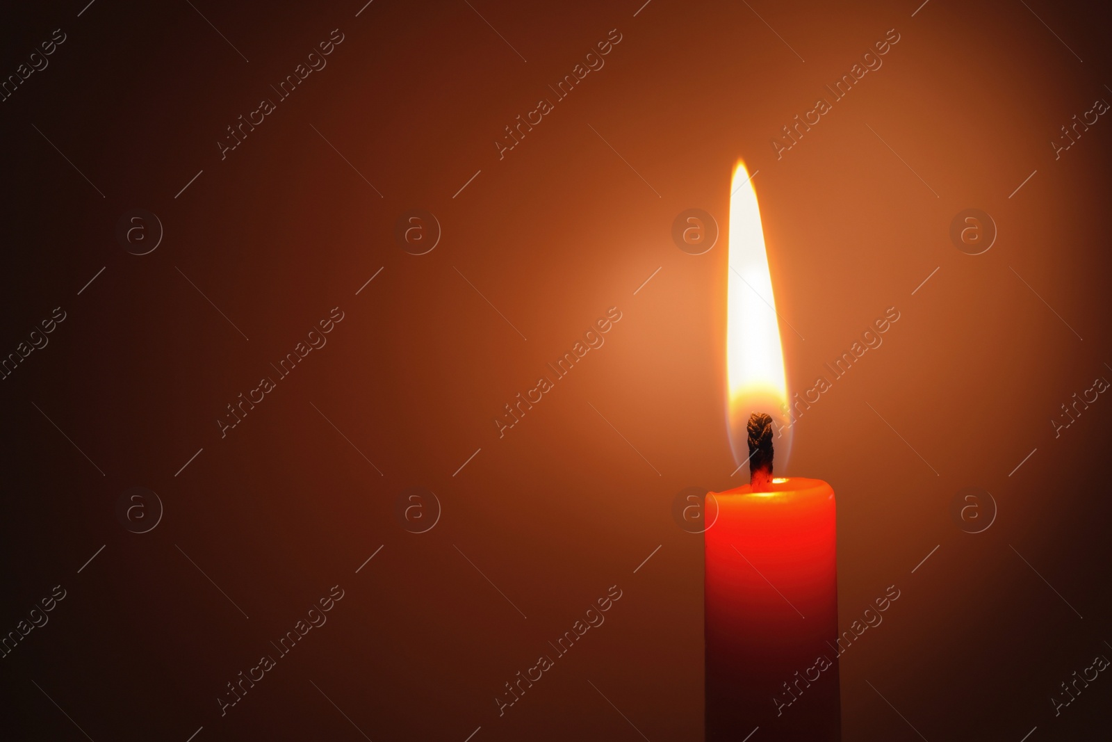 Photo of Wax candle burning in darkness, closeup