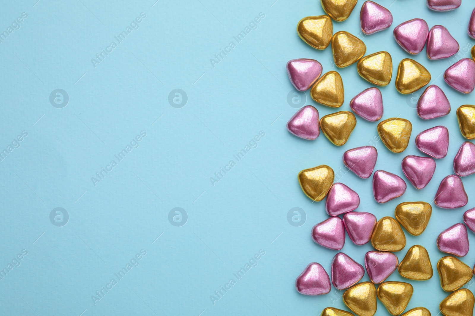 Photo of Many delicious heart shaped candies on light blue background, flat lay. Space for text