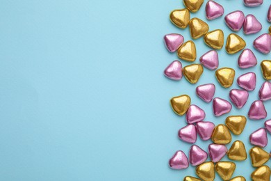 Photo of Many delicious heart shaped candies on light blue background, flat lay. Space for text