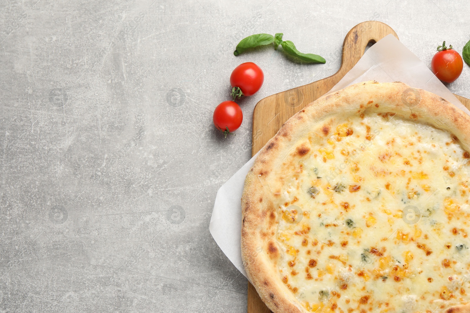 Photo of Delicious cheese pizza, basil and tomatoes on light grey table, flat lay. Space for text