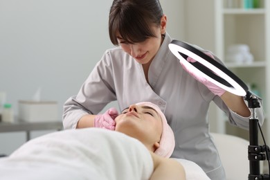 Photo of Cosmetologist making face massage to client in clinic