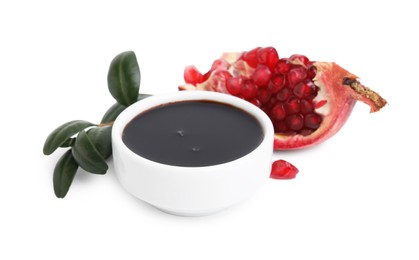 Photo of Tasty pomegranate sauce in bowl, leaves and fruit isolated on white