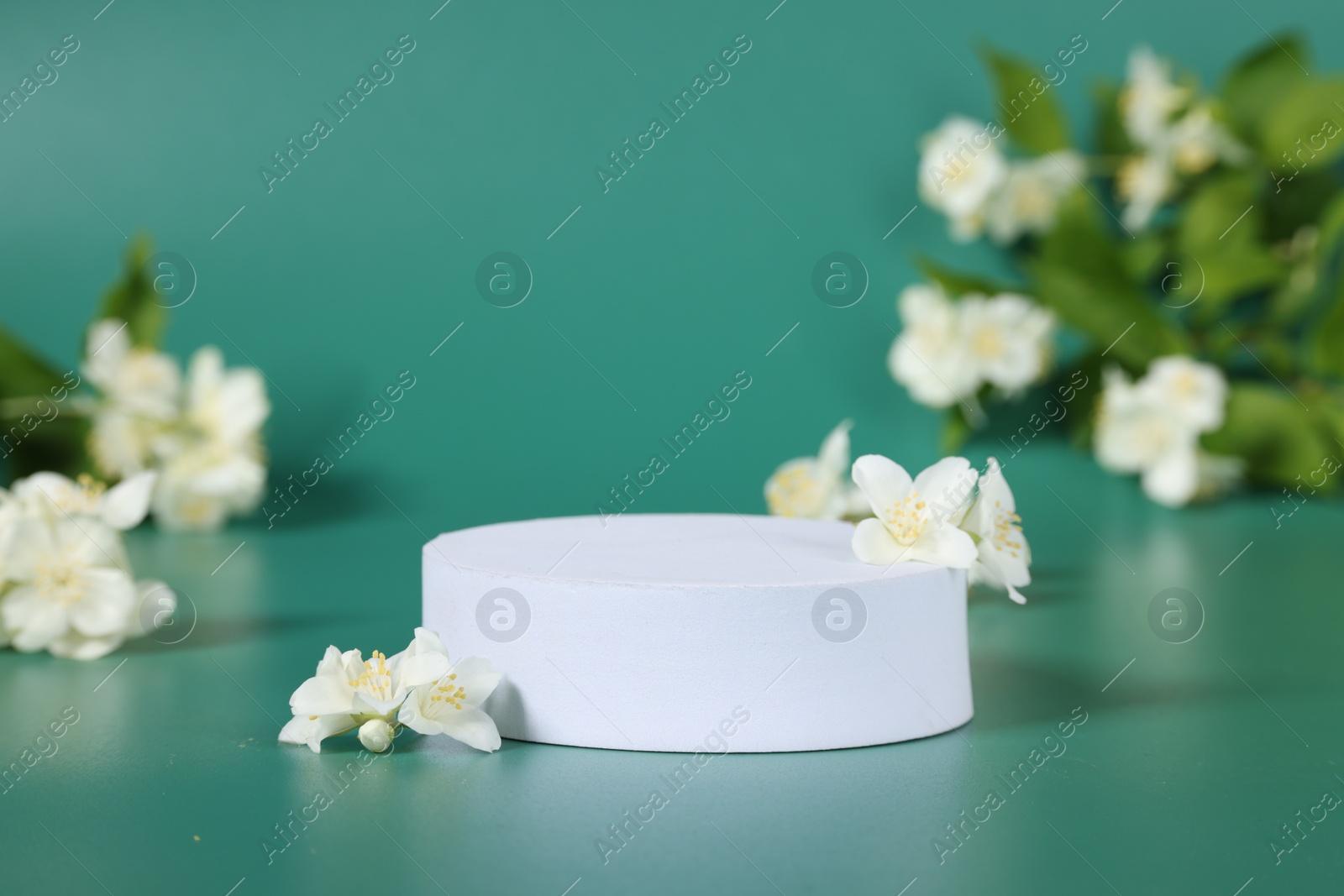 Photo of Presentation of product. White podium and beautiful jasmine flowers on green background