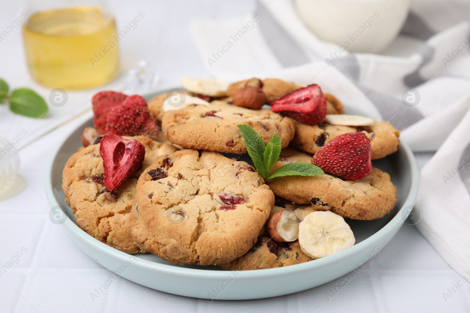 Cookies with freeze dried fruits, mint and nuts on white tiled table, closeup Photo of Cookies with freeze dried fruits, mint and nuts on white tiled table, closeup
