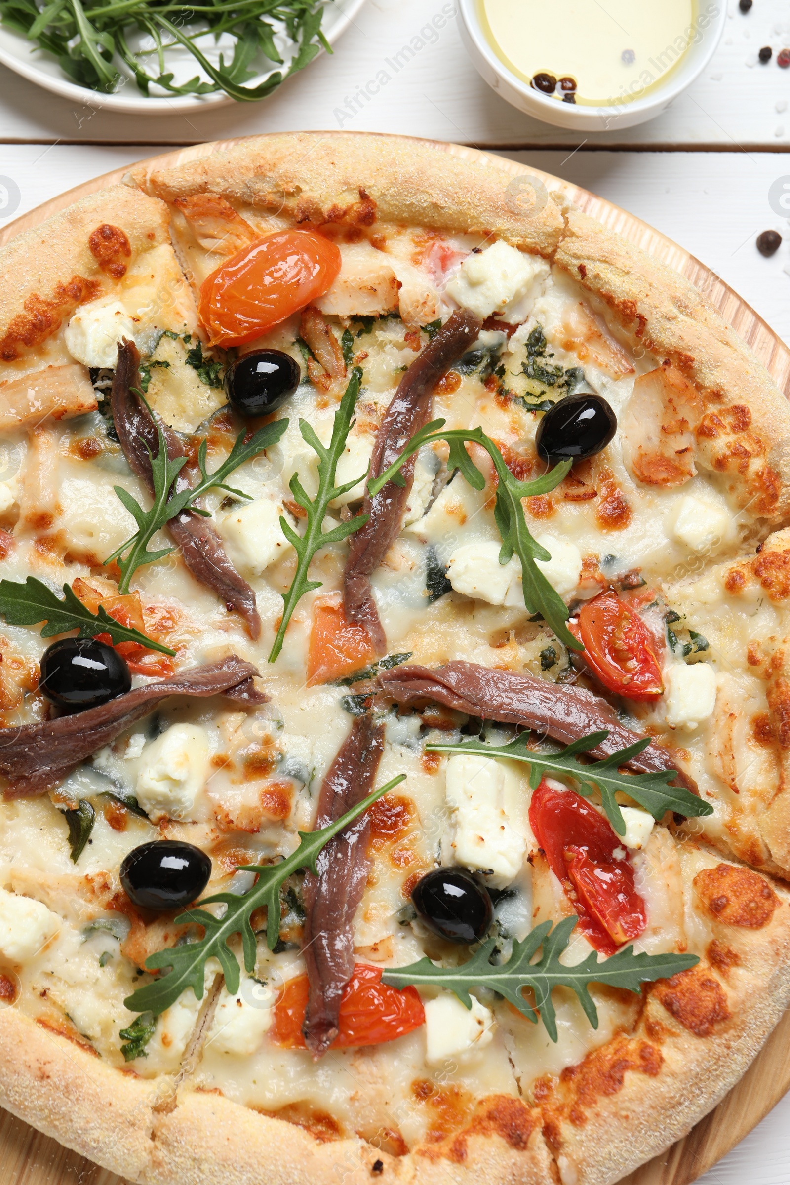 Photo of Tasty pizza with anchovies and ingredients on white wooden table, flat lay