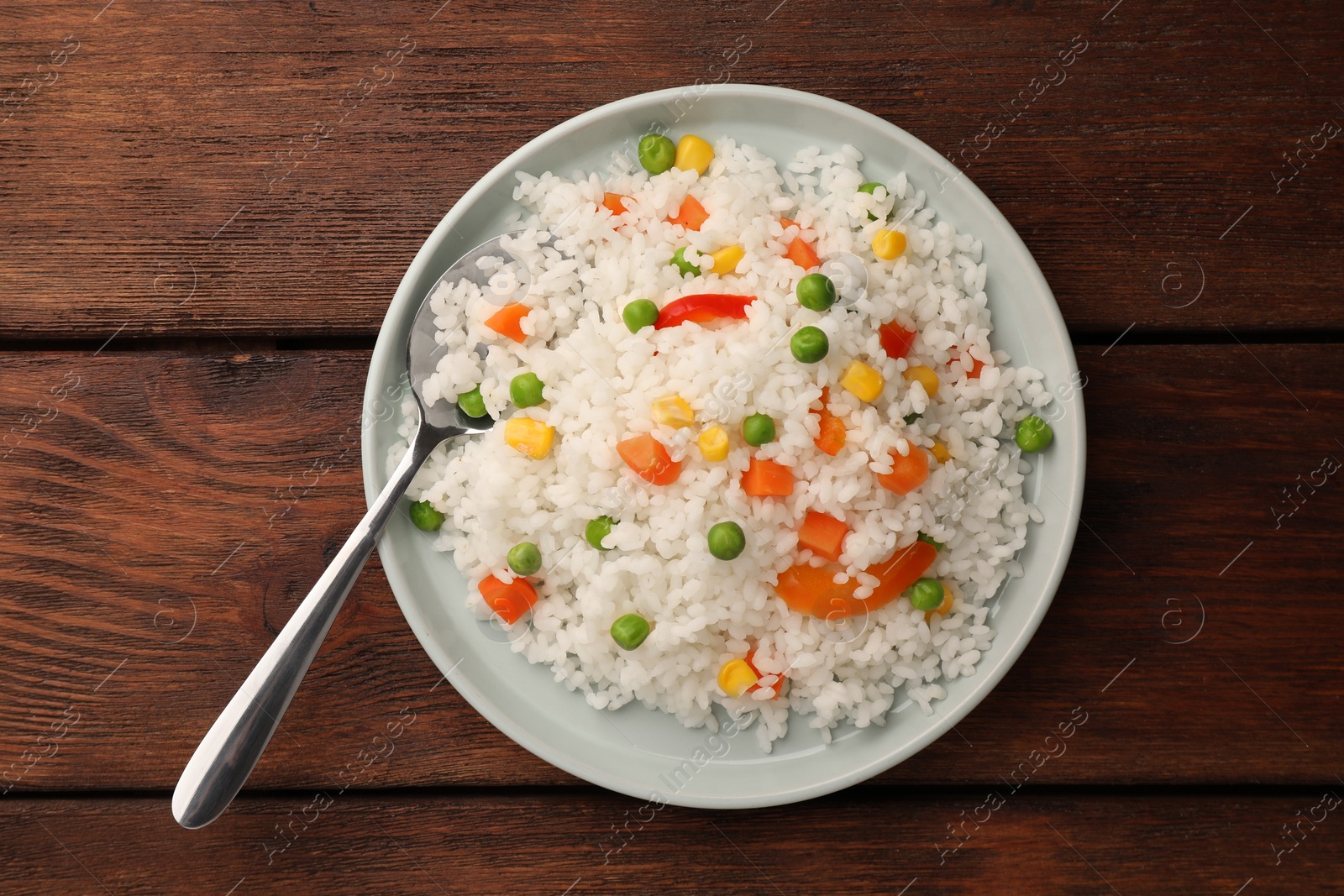 Photo of Delicious rice with vegetables on wooden table, top view