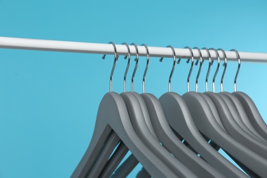 Metal rack with clothes hangers on color background, closeup