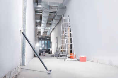 Metal ladder and building materials in hall prepared for renovation