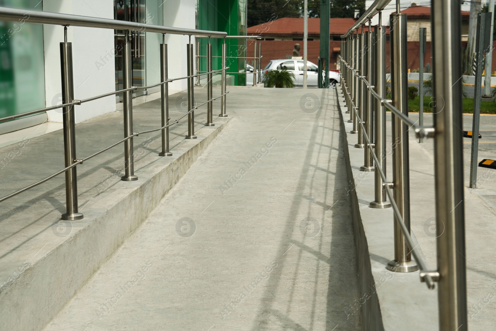 Photo of Concrete ramp with shiny metal railings outdoors