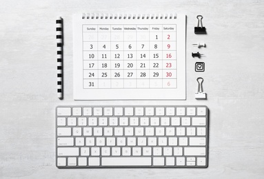 Photo of Wireless keyboard, calendar and office stationery on light table, flat lay