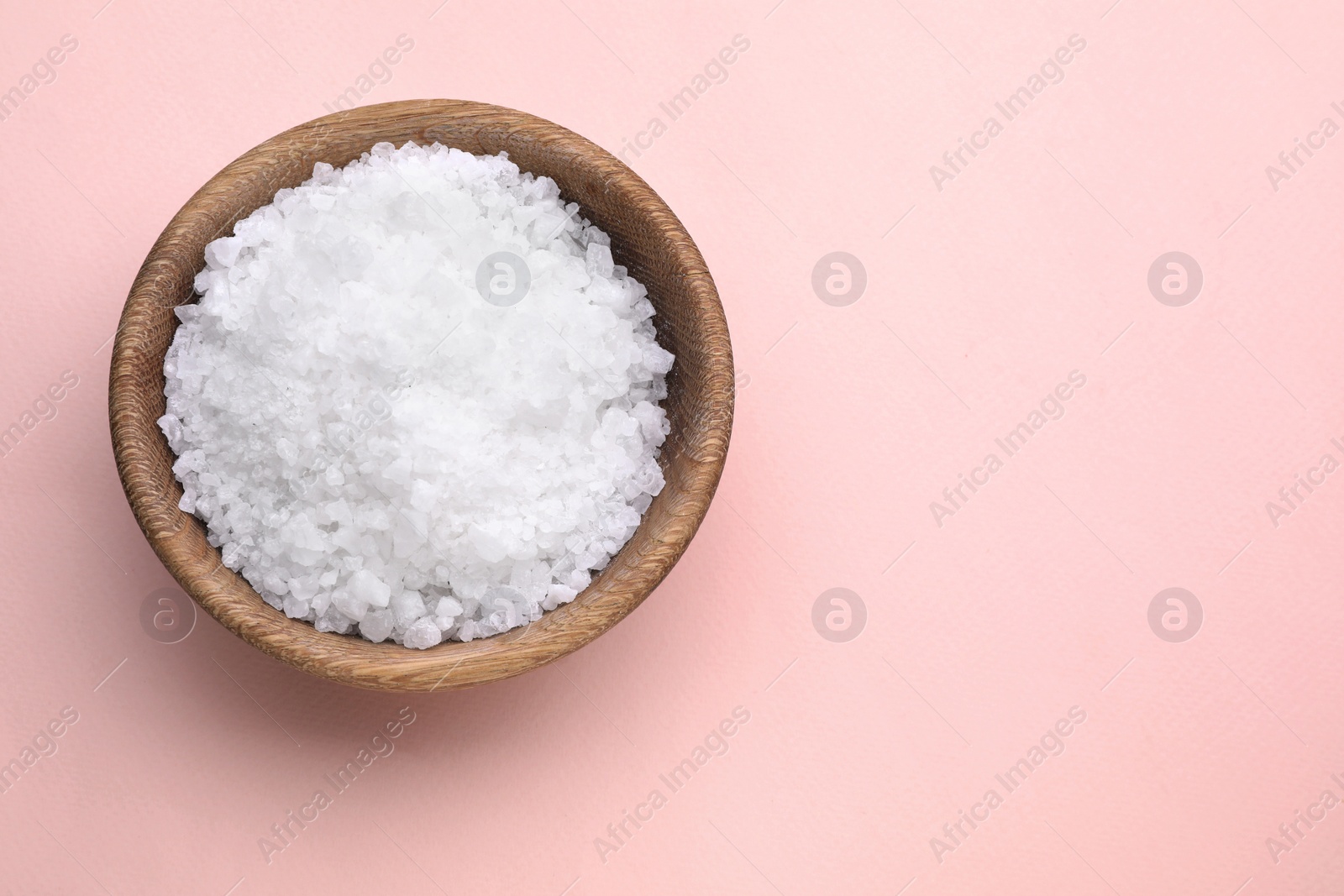 Photo of Bowl with sea salt on pale pink background, top view. Space for text