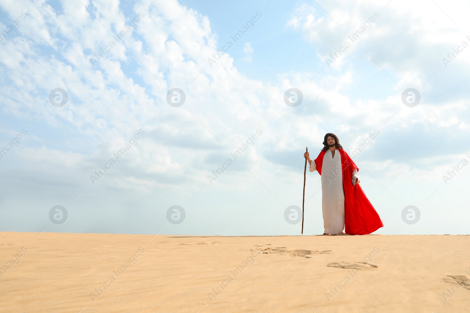 Photo of Jesus Christ walking with stick in desert. Space for text