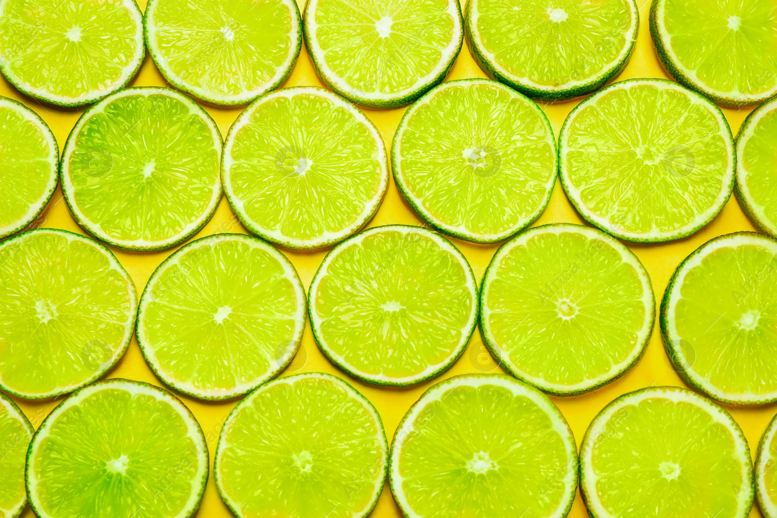 Photo of Juicy fresh lime slices on yellow background, flat lay