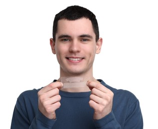 Young man with whitening strips on light background