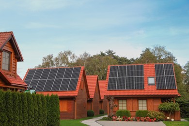 Photo of Beautiful houses with solar panels outdoors. Real estate for rent
