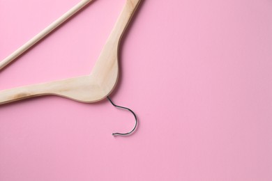 Photo of One wooden hanger on pink background, top view. Space for text