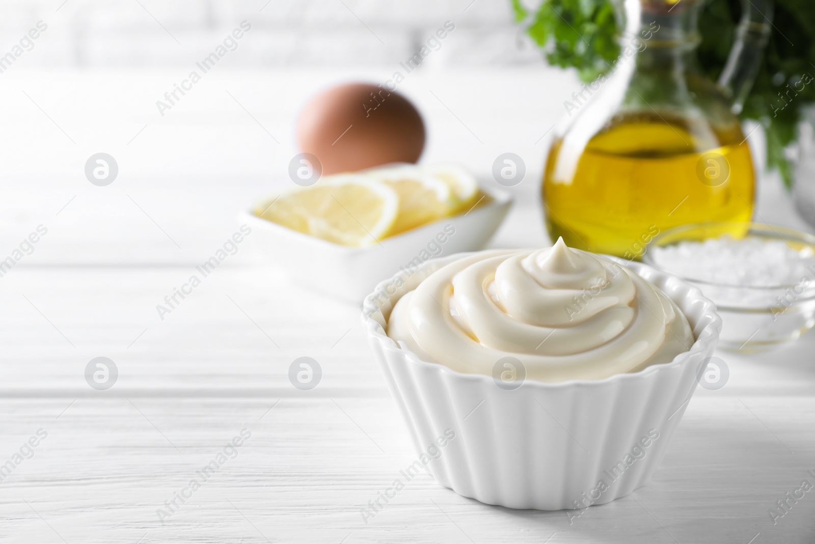 Photo of Fresh mayonnaise sauce in bowl on white wooden table, space for text